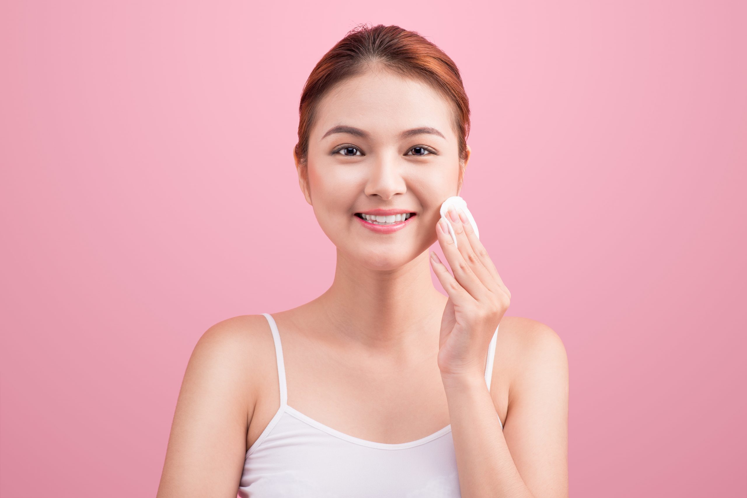 Gorgeous young Korean woman holding cotton pad and smiling in taking ca